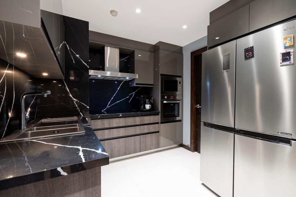 Modern elegance is carried through the kitchen with stainless steel appliances, married with black marble for the countertops and backsplashes. Modern elegance is carried through the kitchen with stainless steel appliances, married with black marble for the countertops and backsplashes.