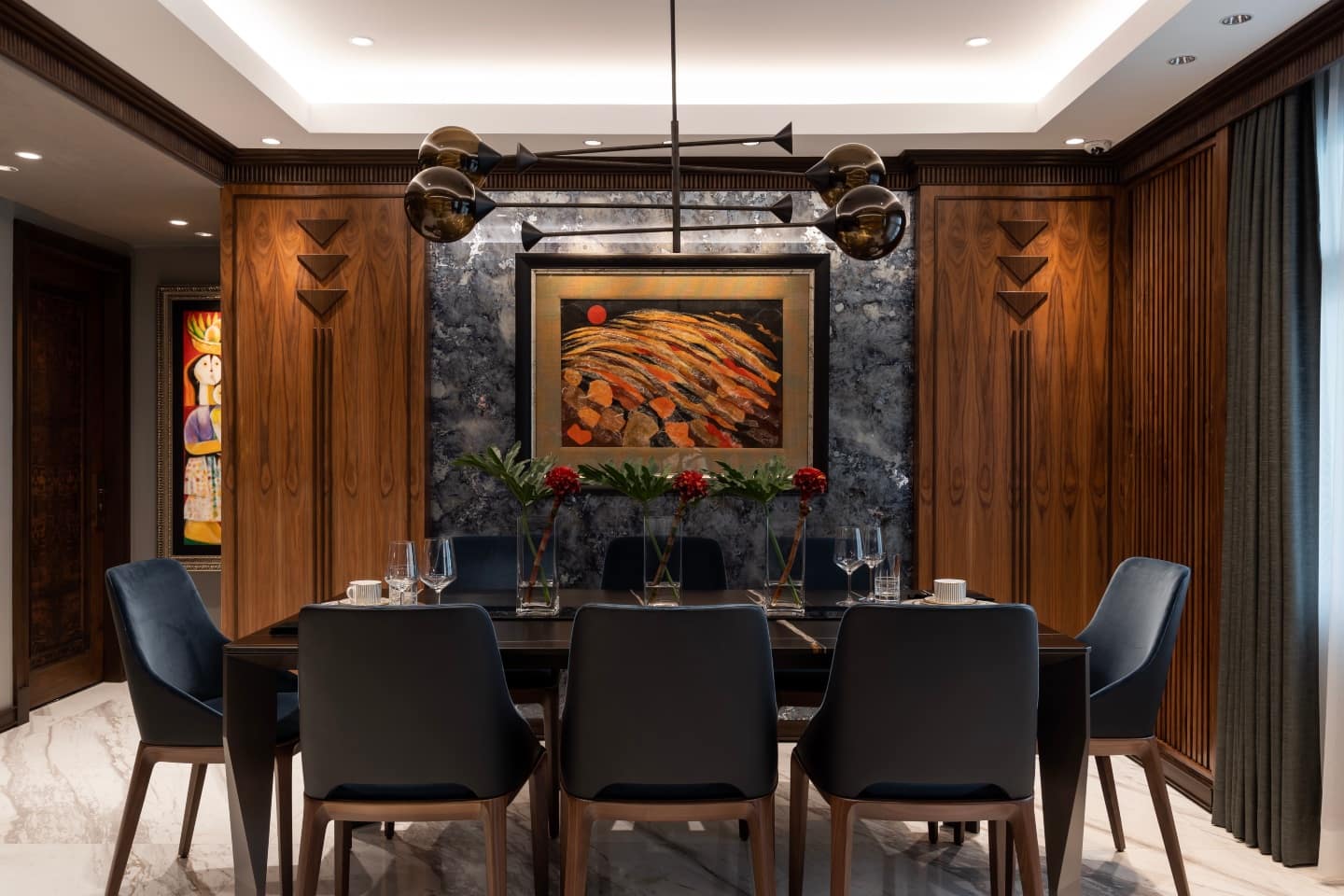 In the dining room, walnut veneers and solid walnut panels to hide the air conditioning units are used. Hints of polished metal finishes, as in the chandelier above the dining table polish the look. In the dining room, walnut veneers and solid walnut panels to hide the air conditioning units are used. Hints of polished metal finishes, as in the chandelier above the dining table polish the look.